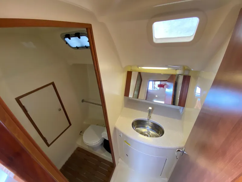 2012 Hunter e36 boat bathroom with sink, toilet, and mirror.