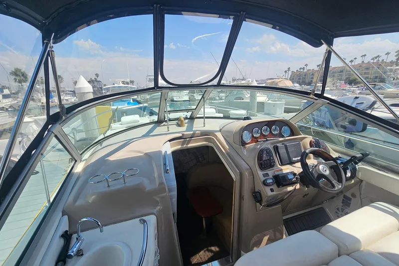 2005 Sea Ray 300 Sundancer cockpit with steering wheel, gauges, and marina view.