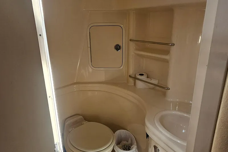 2005 Sea Ray 300 Sundancer bathroom with toilet, sink, and storage shelves.