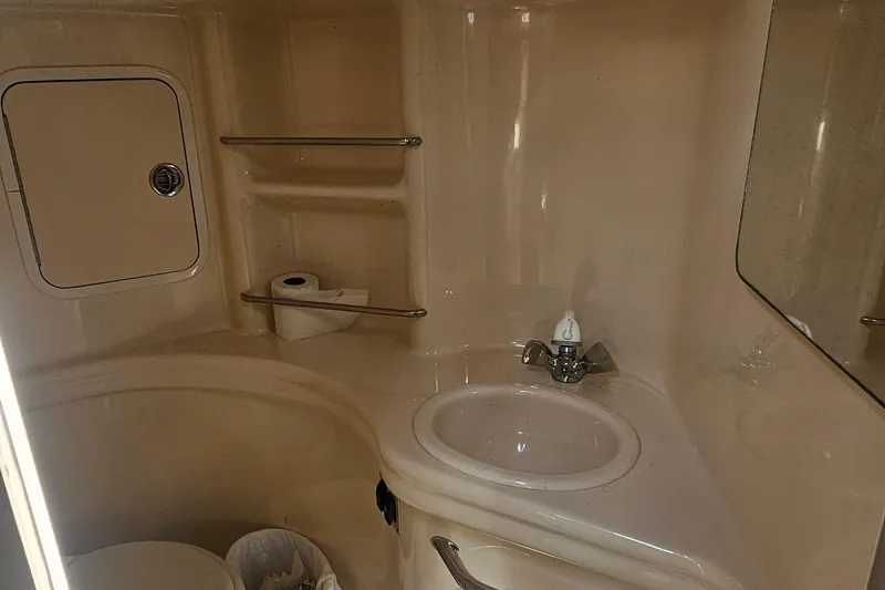 2005 Sea Ray 300 Sundancer bathroom with sink, mirror, and storage shelves.