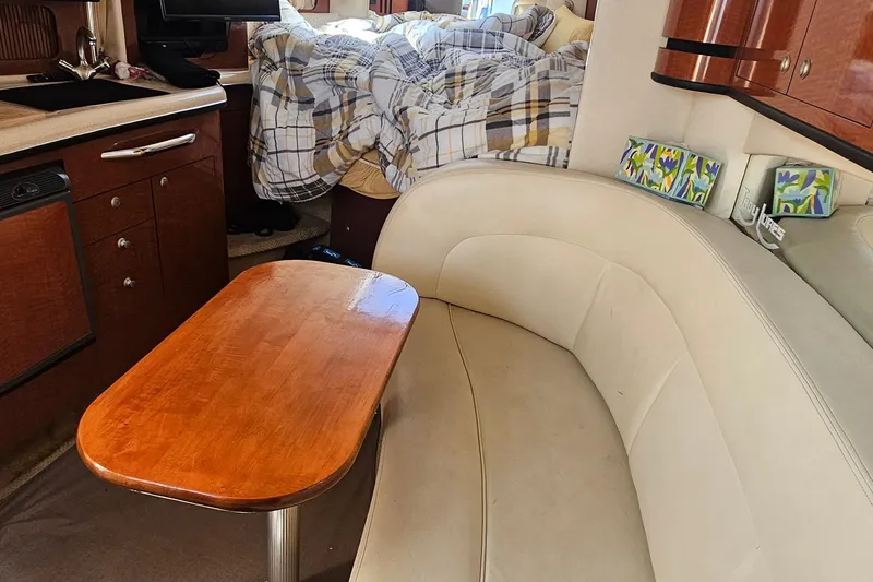 Interior of 2005 Sea Ray 300 Sundancer with cozy seating and wooden table.