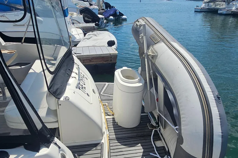 2005 Sea Ray 300 Sundancer docked with inflatable boat and marina view.