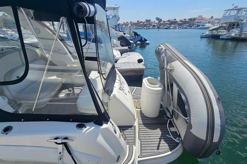 2005 Sea Ray 300 Sundancer docked with inflatable boat, marina view.