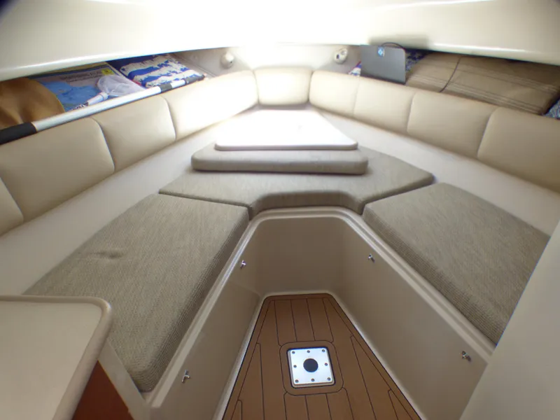 2004 Robalo R265 Walkaround cabin interior with beige seating and wooden flooring.