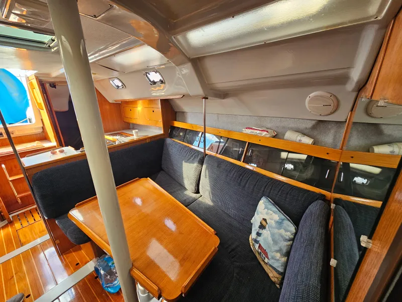 Interior of a 1988 Hunter Legend 35 yacht with wooden table and blue upholstery.