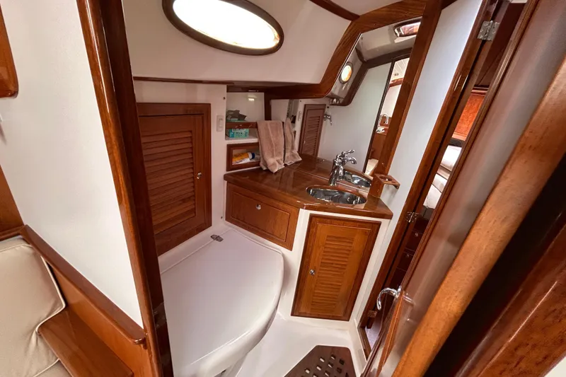 2015 Alerion Coastal Cruiser interior with wooden cabinetry and compact bathroom.