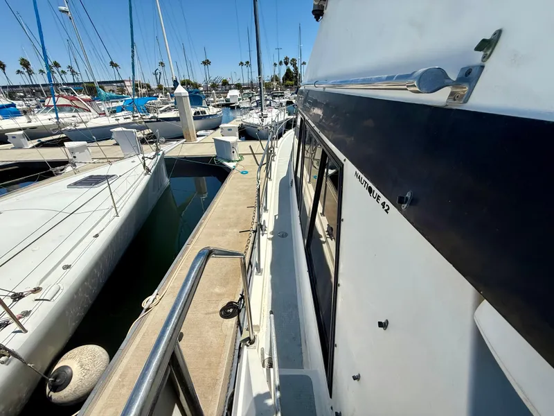 1986 Kha Shing Nautique yacht docked at marina, surrounded by sailboats under clear blue sky.
