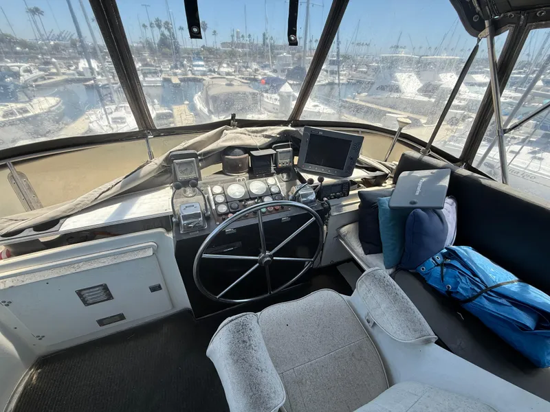 1986 Kha Shing Nautique boat cockpit with steering wheel, navigation equipment, and marina view.