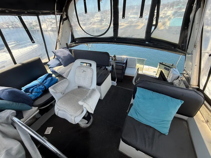 Interior of 1986 Kha Shing Nautique boat with seating and cushions, overlooking marina.