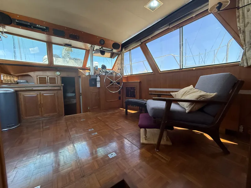 Interior of 1986 Kha Shing Nautique yacht with wooden decor and large windows.