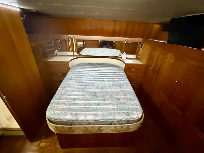 1986 Kha Shing Nautique yacht bedroom with wooden cabinetry and a central bed.