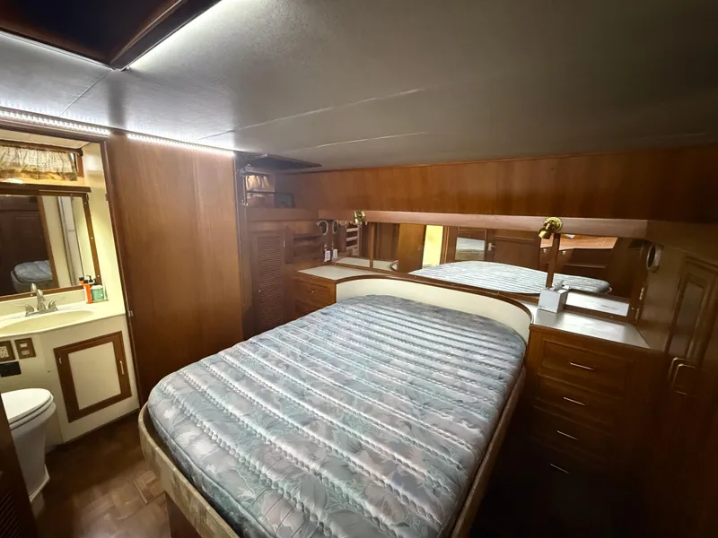 1986 Kha Shing Nautique yacht bedroom with wood paneling and cozy bed.