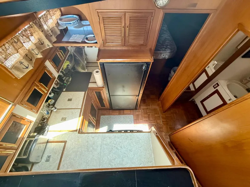 Interior of 1986 Kha Shing Nautique yacht, featuring kitchen and living area with wooden cabinetry.