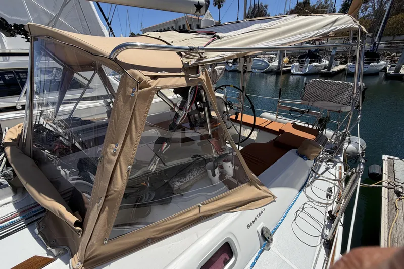 2010 Beneteau Oceanis 37 sailboat with tan canopy docked in marina.