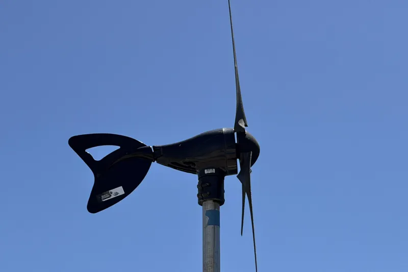 Wind turbine on a Beneteau Oceanis 37 sailboat, 2010 model, against clear blue sky.