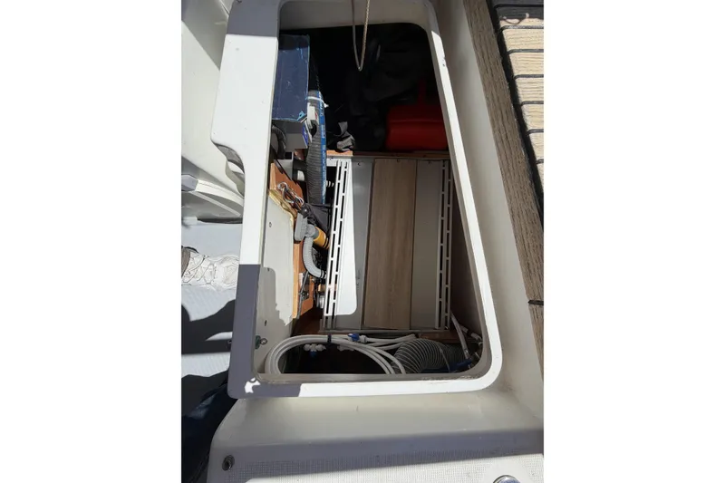Storage compartment of a 2010 Beneteau Oceanis 37 sailboat, showing interior equipment and cables.