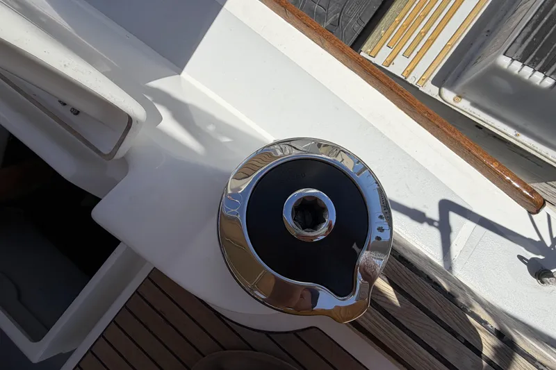 Winch on 2010 Beneteau Oceanis 37 sailboat deck, featuring wood and metal details.