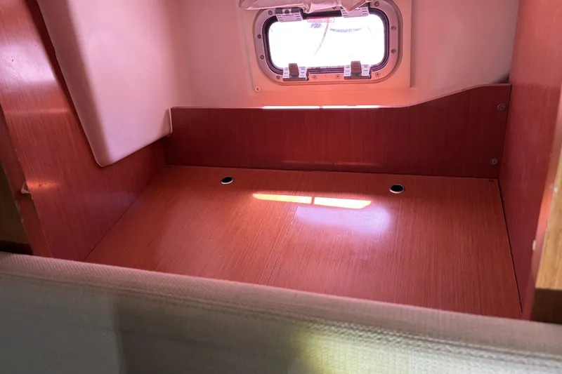 Interior cabin space of 2010 Beneteau Oceanis 37 sailboat, featuring wooden finish and porthole.