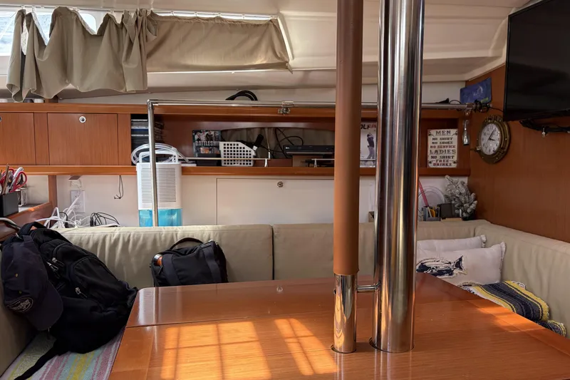 Interior of a 2010 Beneteau Oceanis 37 sailboat, featuring cozy seating and wooden finishes.