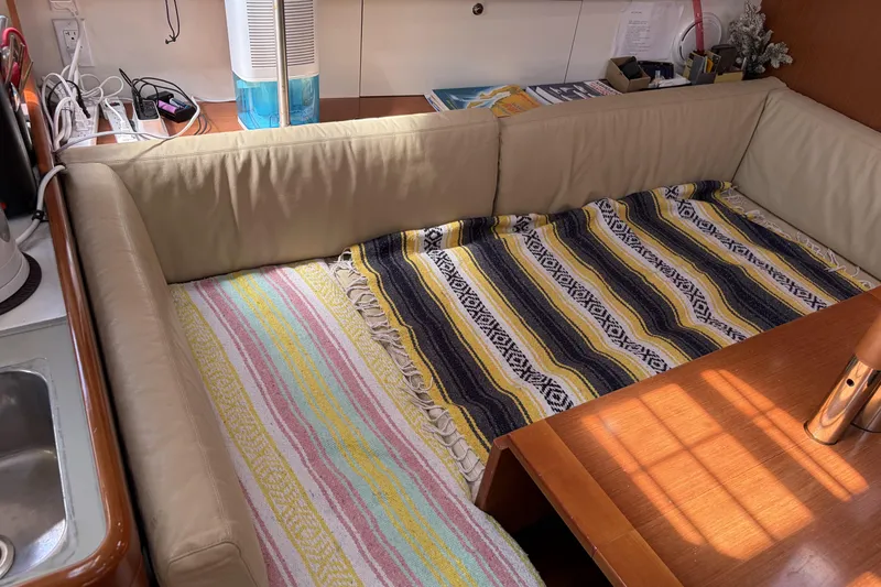 Interior of 2010 Beneteau Oceanis 37 yacht with cozy seating and colorful blankets.