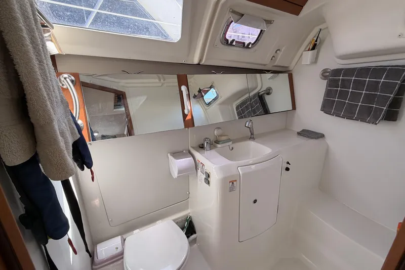 Bathroom interior of a 2010 Beneteau Oceanis 37 yacht, featuring a sink, mirror, and toilet.