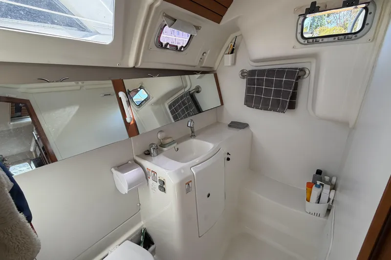 Bathroom interior of a 2010 Beneteau Oceanis 37 yacht, featuring sink, mirror, and toiletries.