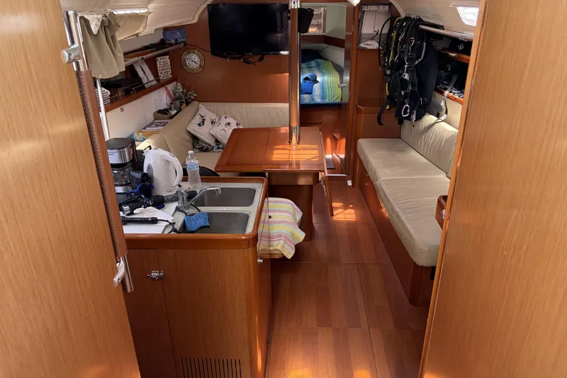 Interior of a 2010 Beneteau Oceanis 37 sailboat, featuring cozy seating and a compact kitchen area.