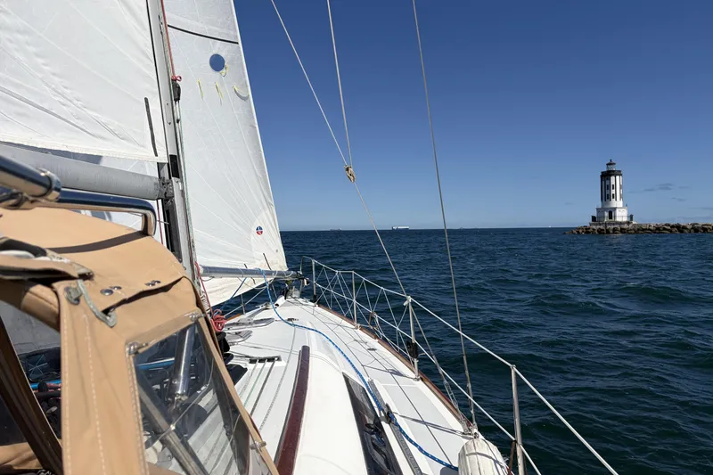 Sailing Beneteau Oceanis 37 near lighthouse on clear day, 2010 model.