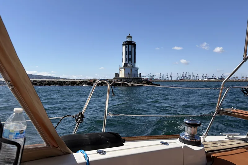 Beneteau Oceanis 37 sailing near a lighthouse with cranes in the background, 2010 model.