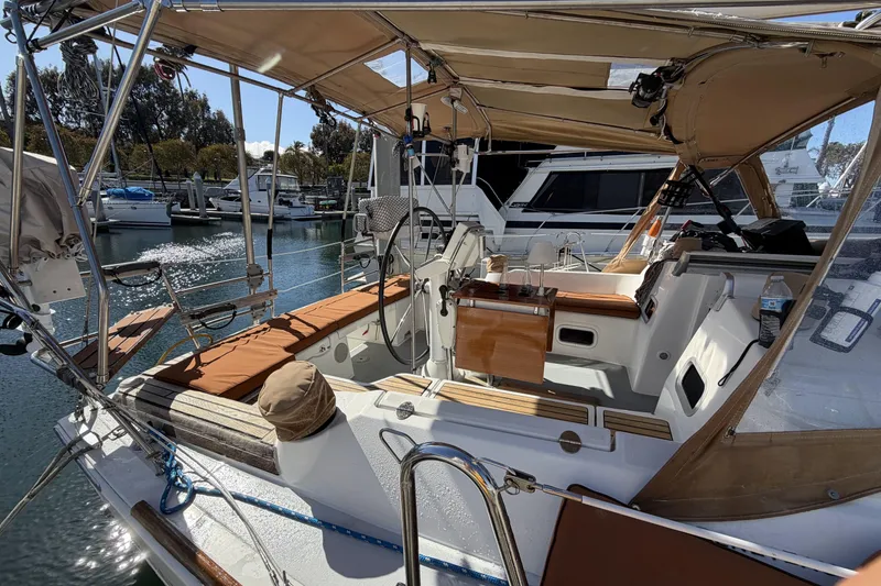 2010 Beneteau Oceanis 37 sailboat cockpit with tan cushions and marina backdrop.