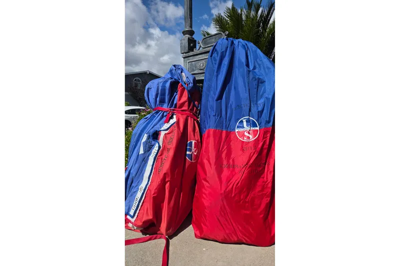 Red and blue sail bags on pavement, suitable for Beneteau Oceanis 37, 2010 model.