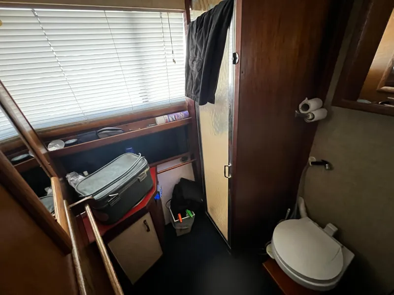 1982 Carver Mariner 33 bathroom with toilet, shower, and storage shelves.