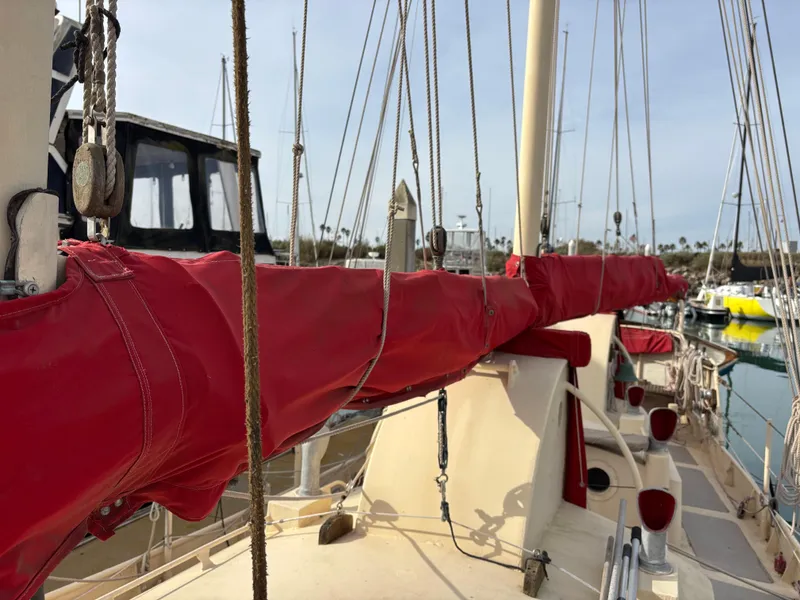 1975 Custom 45’ Thomas Colvin “Tamarack” Schooner with red sail cover in marina.