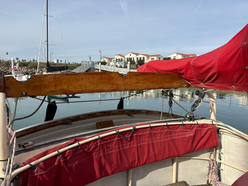 1975 Custom 45’ Thomas Colvin “Tamarack” Schooner with red sail cover in a marina setting.