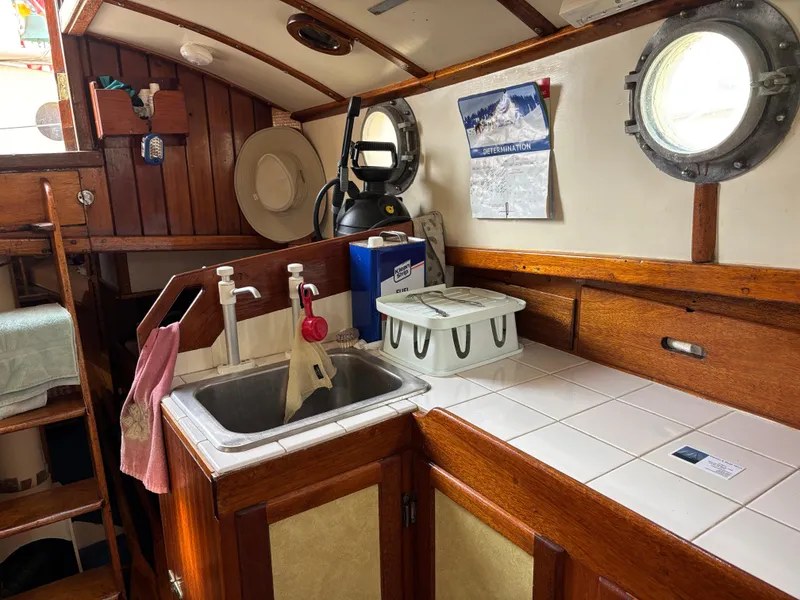 Interior of 1975 Custom 45’ Thomas Colvin “Tamarack” Schooner with wooden cabinetry and porthole.