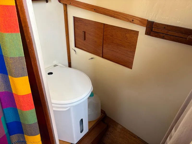 Compact bathroom with a white toilet on a 1975 Custom 45’ Thomas Colvin “Tamarack” Schooner.