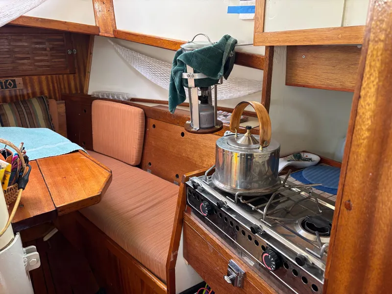 Cozy interior of 1975 Custom 45’ Thomas Colvin “Tamarack” Schooner with stove and seating area.
