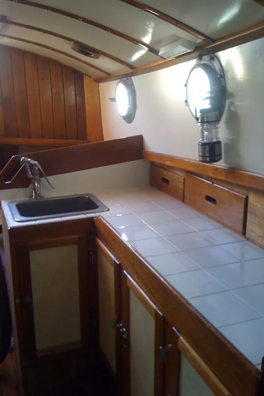 Interior of 1975 Custom 45’ Thomas Colvin “Tamarack” Schooner with wooden cabinetry and porthole.