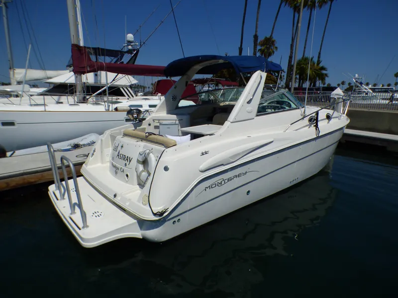 2001 Monterey 302 Cruiser docked at marina, clear sky, palm trees in background.