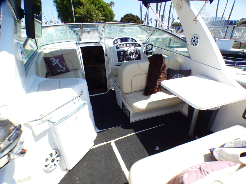 2001 Monterey 302 Cruiser interior with seating, table, and helm, featuring nautical decor.