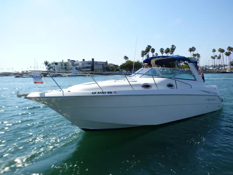2001 Monterey 302 Cruiser boat on water, for sale, sunny day, palm trees in background.