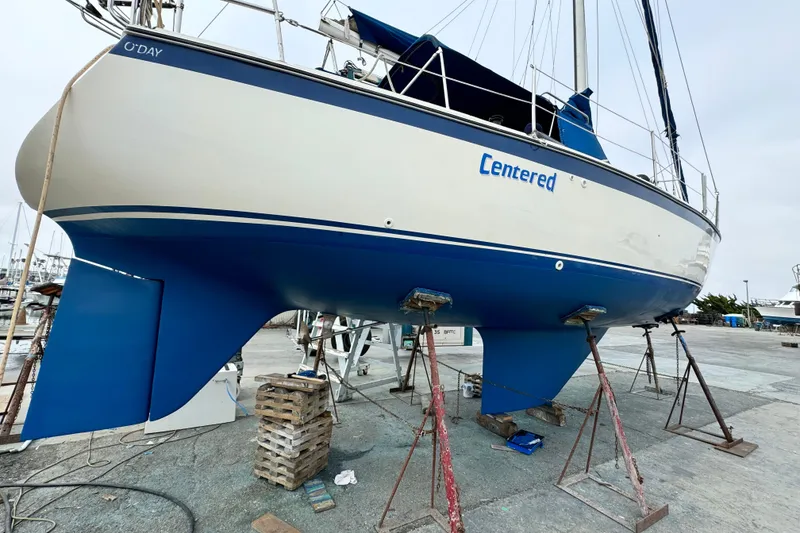 1979 O'Day 37 Center Cockpit sailboat on stands, blue and white hull, marina background.