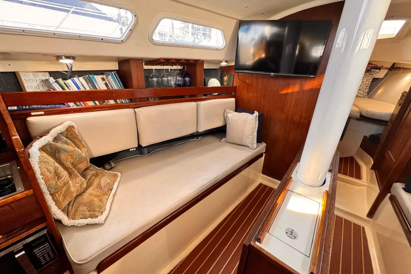 1979 O'Day 37 Center Cockpit interior with cozy seating, bookshelves, and mounted TV.