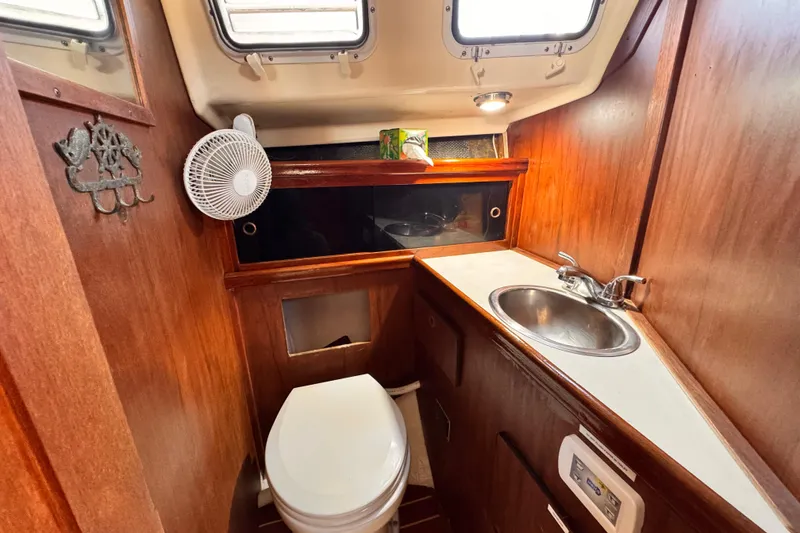 1979 O'Day 37 Center Cockpit bathroom with sink, toilet, and wooden cabinetry.