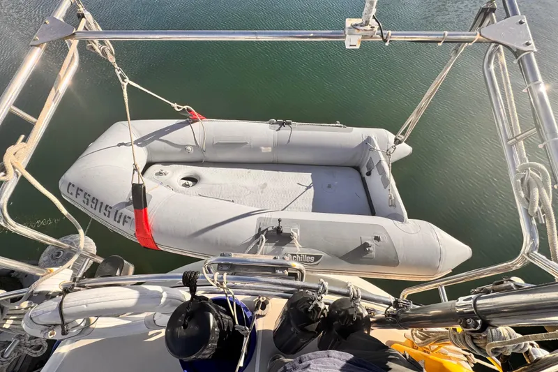 Inflatable dinghy suspended from 1979 O'Day 37 Center Cockpit sailboat over water.