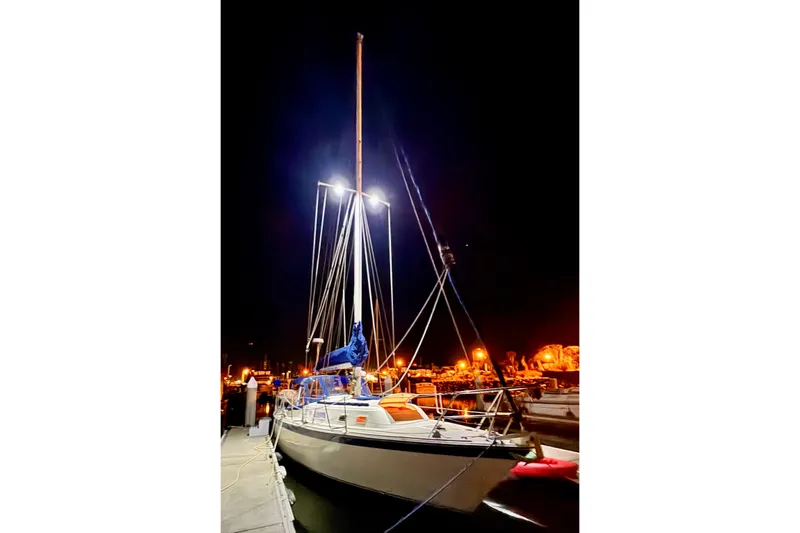 1979 O'Day 37 Center Cockpit sailboat docked at night, illuminated by bright lights.