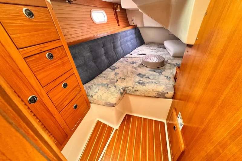 Cozy cabin interior of 2001 Catalina 36 MkII sailboat with wooden cabinetry and cushioned bed.
