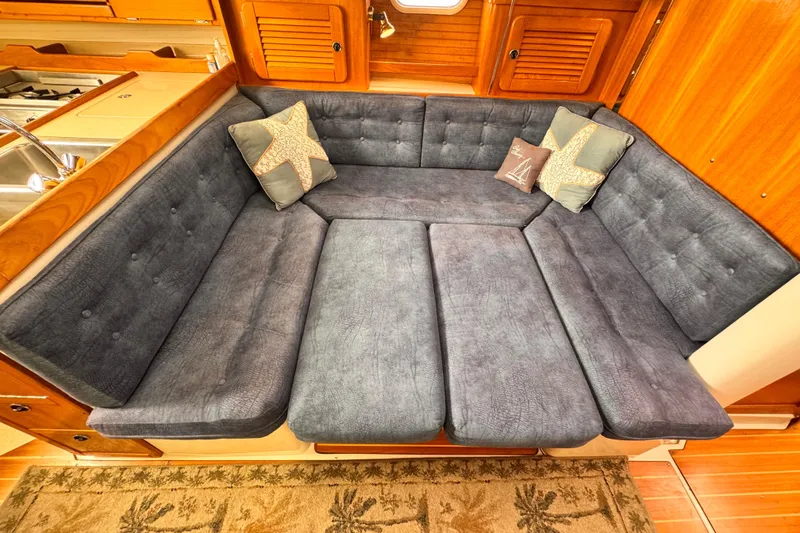 Luxurious interior of 2001 Catalina 36 MkII sailboat with plush seating and nautical-themed pillows.