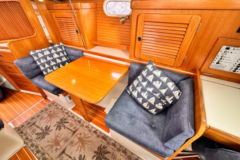 Cozy interior of 2001 Catalina 36 MkII sailboat with wooden table and cushioned seating.