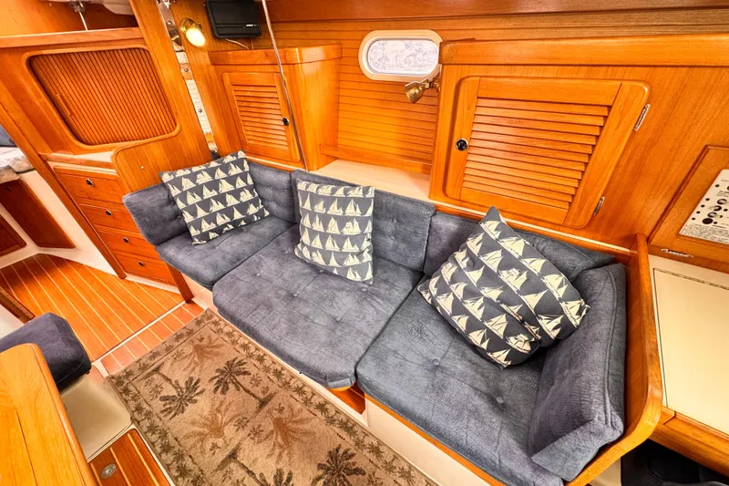 Cozy interior of 2001 Catalina 36 MkII sailboat with blue cushions and nautical pillows.